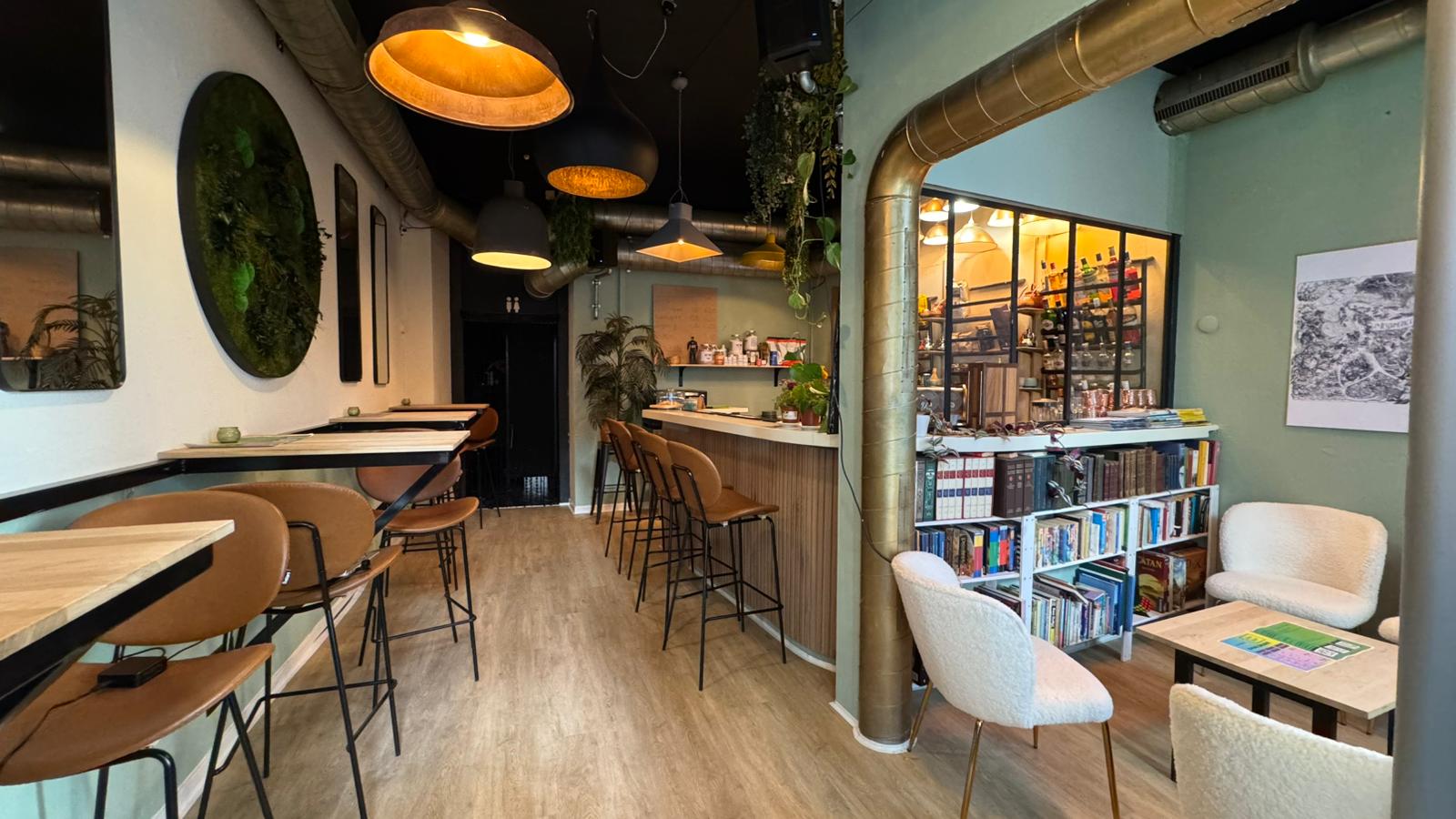 KAFKAF café-bar interior — warm lights, plants, and the full bar